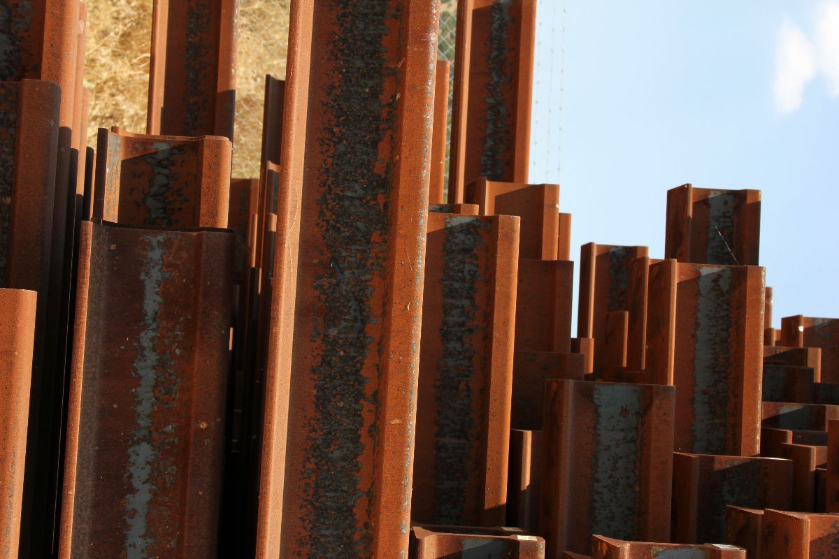 Rusty steel beams stored outdoors under direct weather exposure