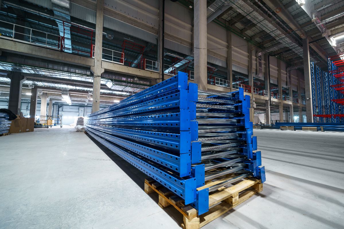 Blue steel beams stacked on pallets inside an industrial warehouse