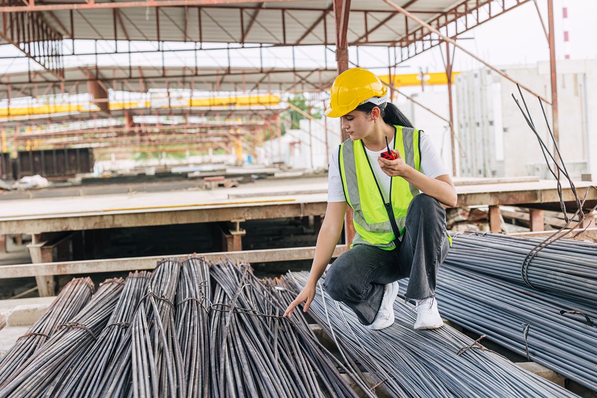 Construction worker inspecting bundled steel bars on site, representing engineering and detailing in structural steel projects
